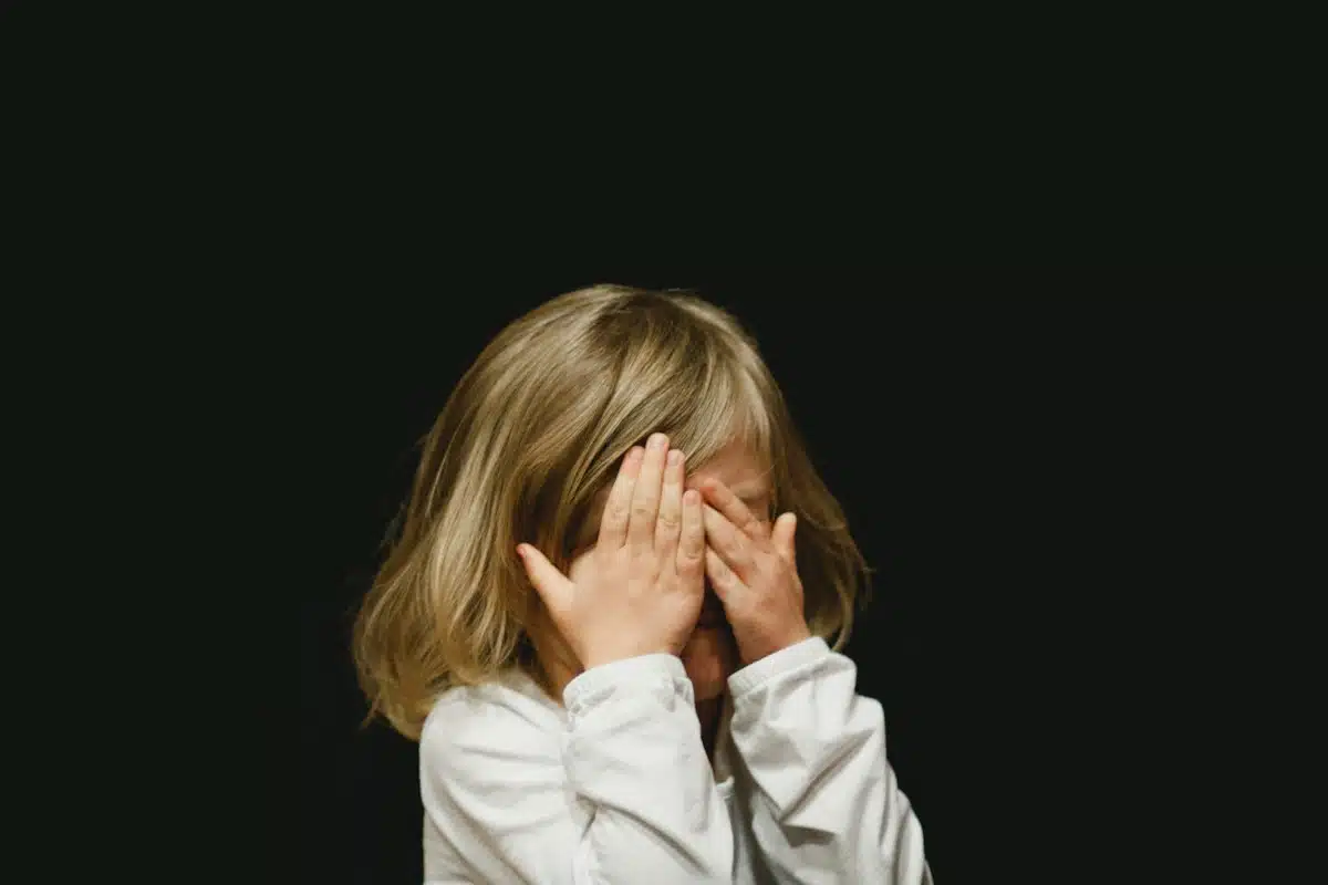 Enfant qui cache son visage dans ses mains