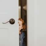 Petite fille qui se cache derrière une porte, image des blessures d'enfance