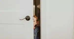 Petite fille qui se cache derrière une porte, image des blessures d'enfance